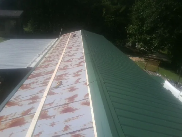 Old rusted panels beside newly installed green metal roofing — Wind Damage Roof Repair by Roofing Brothers in Bonita Springs