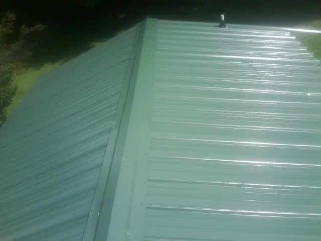 New green metal panels meeting at the ridge of a roof — Flat Roof Repair work by our crew in Bonita Springs