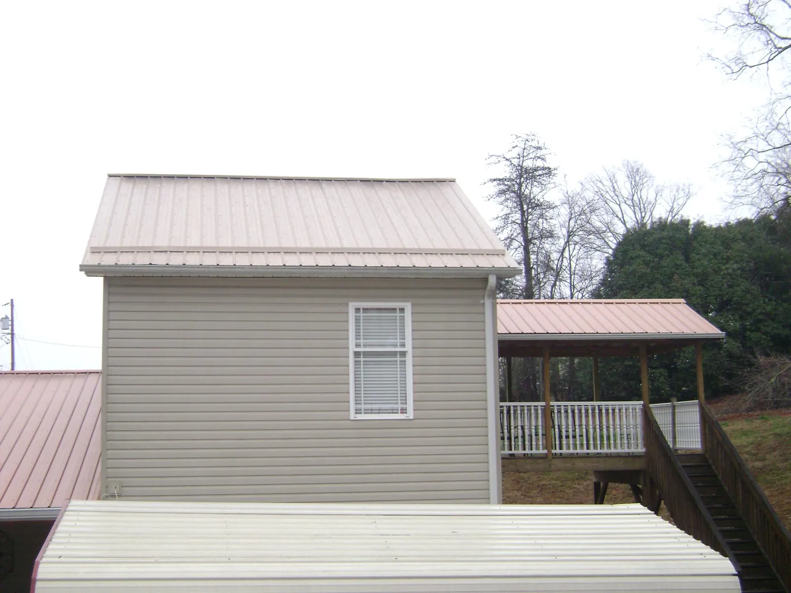 Tan metal roofs on a two story addition and attached porch, from a Roof Replacement job in Bonita Springs