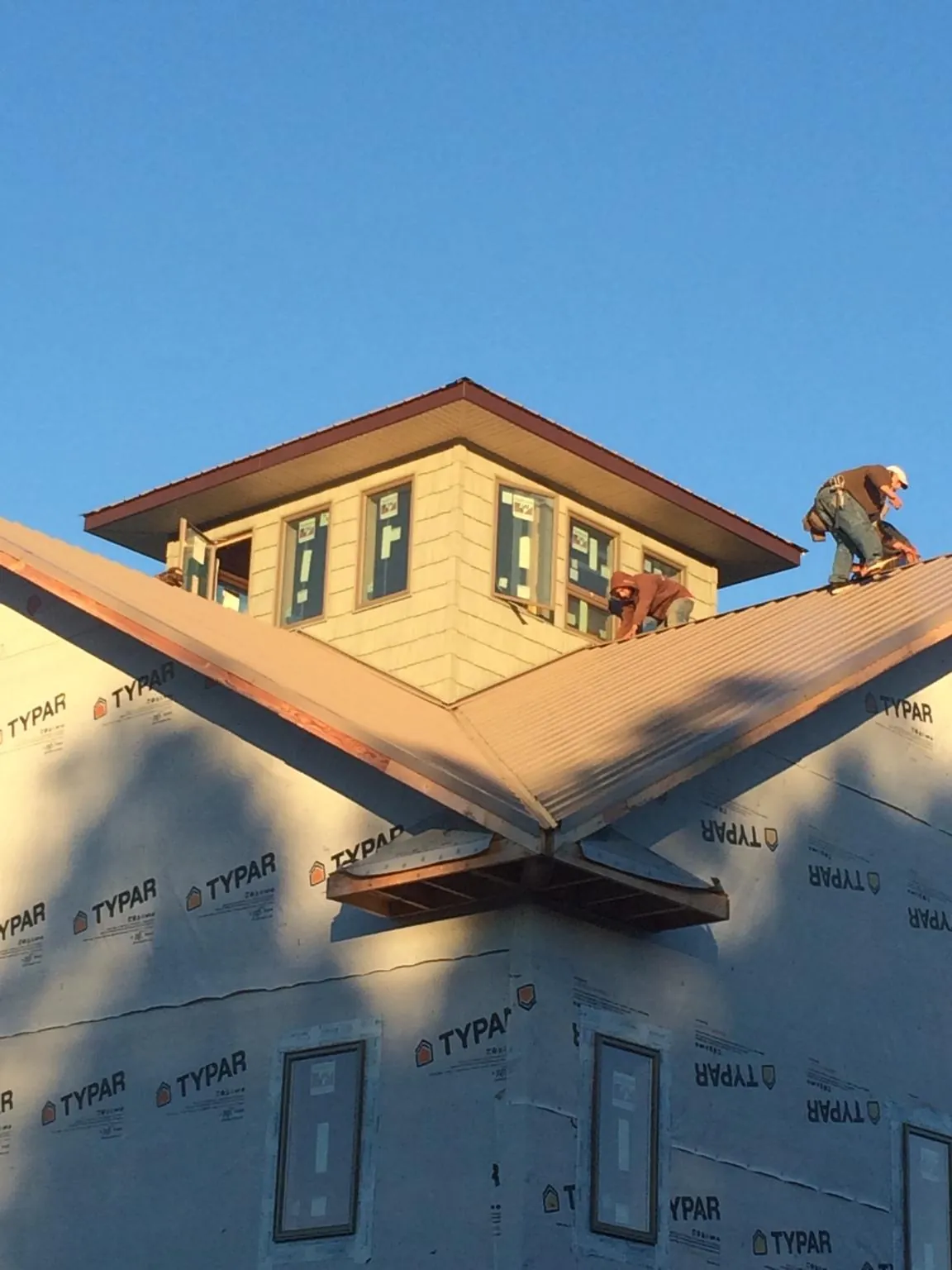 Roofers working around a rooftop cupola on a new metal roof at sunset — Roof Waterproofing in Bonita Springs by Roofing Brothers